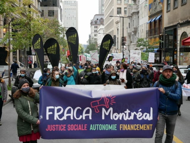 Des centaines de personnes marchent derrière la bannière du FRACA Montréal pendant la manif Coup de sifflet pour la CAQ-25 oct 2021